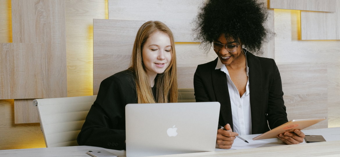 White and black business women looking at computer together